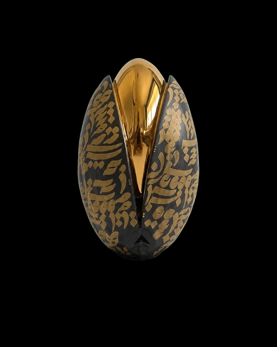 Black and gold ceramic piece shaped like a split pistachio shell with a gold interior